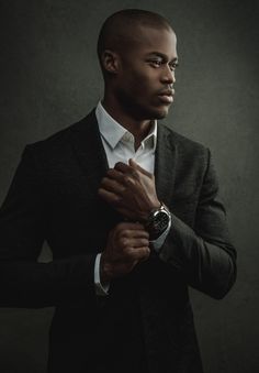 a man in a suit and white shirt is holding his hands together while wearing a watch