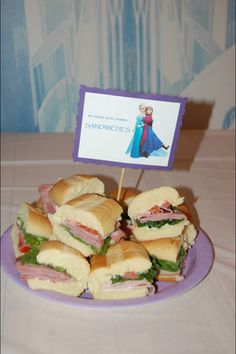 a plate full of sandwiches on a table with a sign in the middle that says sandwiches