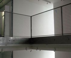 an empty room with metal railings and mirrors on the wall, in front of a window