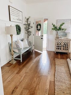 a living room with wood floors and white walls is pictured in this image from the entryway