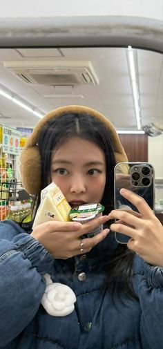 a woman taking a selfie with her cell phone in front of the camera while holding some food