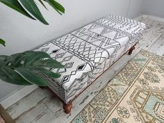 a bench with a cushion on top of it next to a potted plant and rug