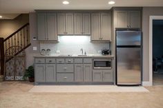 an empty kitchen with stainless steel appliances and wood cabinets in the center, stairs leading up to the second floor