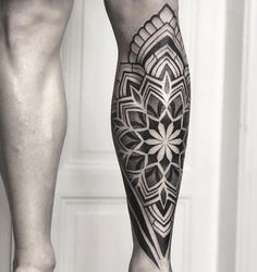 a man's leg with a black and white tattoo design on the lower part of his leg