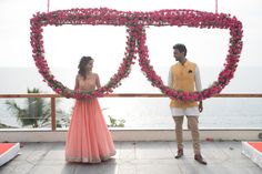 a man and woman standing next to each other in front of a heart shaped frame