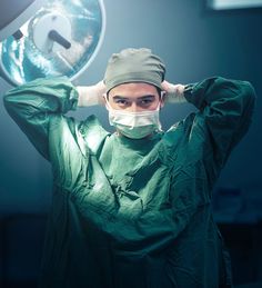 a male surgeon in scrubs is holding his head