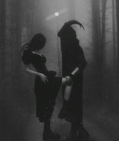 two women dressed in black standing in the woods