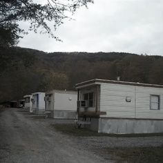 two mobile homes are parked on the side of a dirt road