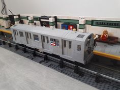 a toy train is on the tracks in front of a model station with legos