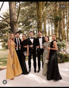 a group of people standing next to each other in formal wear and holding wine glasses