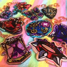 several different shaped key chains on a colorful surface with flowers and hearts in the center