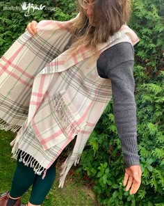 a woman is standing in front of some bushes wearing a plaid scarf and green leggings