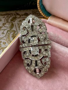 The 1940 art deco rhinestone duette brooch is a radiant testament to vintage glamour. Adorned with baguette and round clear crystals, it exudes timeless elegance. Every stone gleams brightly, reflecting the era's opulence. This versatile piece showcases the duette's unique feature, allowing it to transform into dress or shoe clips, offering varied styling options beyond its traditional brooch function. With no missing stones, it maintains its original allure. Measuring 2-1/2 inches in width and Glamorous Silver Brooch For Wedding, Art Deco Diamond Jewelry For Evening, Art Deco Diamond Evening Jewelry, Art Deco Diamond Brooch For Evening, Art Deco Jewelry With Diamond Accents For Evening, Silver Art Deco Brooches For Wedding, Art Deco Diamond Brooches For Evening, Silver Art Deco Wedding Brooch, Silver Art Deco Wedding Brooches