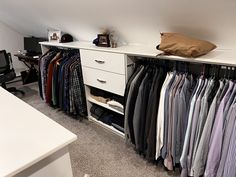 an organized closet with clothes hanging on the shelves and drawers, along with a computer desk