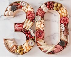 the number 50 made out of cheese, meats and other foods on a marble surface