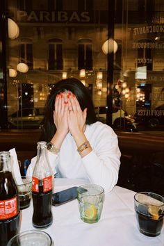 a woman sitting at a table with her hands covering her face