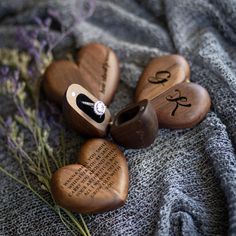 three wooden heart shaped boxes with names on them sitting on top of a gray blanket