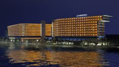 the hotel is lit up at night on the water