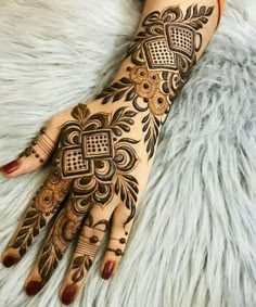 a woman's hand with henna tattoos on it and some flowers in the middle