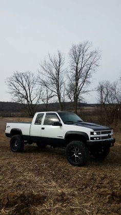 a white truck parked on top of a dry grass field