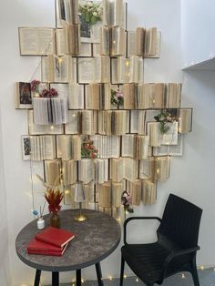 there is a table with books on it next to a chair and a wall decoration