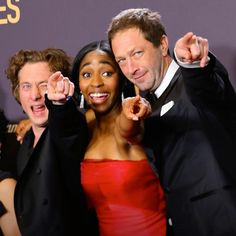 two men and a woman posing together on the red carpet at an awards event with their hands in the air