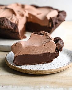 a piece of chocolate pie on a plate with a slice taken out of it and the rest of the pie in the background