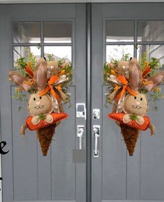 two bunny decorations on the front door of a house, each decorated with carrots and grass