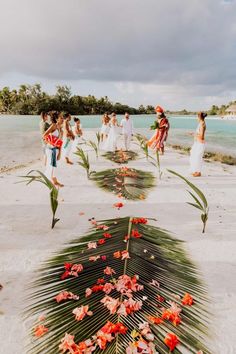 people are standing on the beach with flowers