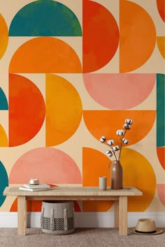 a table with vases on it in front of a wall painted with colorful circles