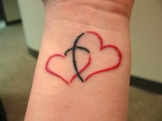 two hearts on the wrist with an arrow and cross drawn in it's center