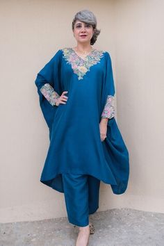 Blue kaftan with resham, zardozi applique embroidered V neck and sleeve cuffs. Paired with printed straight fit pant.
Components: 2
Pattern: Applique Embroidered
Type Of Work: Resham and Zardozi Work
Neckline: V Neck
Sleeve Type: Batwing Sleeves
Fabric: Pure Silk
Color: Blue
Other Details: 
Cut work hem details
Asymmetric hem on kaftan
Note: The outfit worn by the other model on the left is not for sale
Occasion: Mehendi and Haldi,Sangeet - Aza Fashions Blue Bollywood Style Abaya For Eid, Unstitched Blue Kaftan For Eid, Blue Kaftan With Zari Work For Diwali, Blue Kaftan With Zari Work For Wedding, Blue Dabka Work Kaftan For Wedding, Blue Kaftan For Eid With Traditional Drape, Blue Traditional Drape Kaftan For Eid, Blue Wedding Kaftan With Zari Work, Blue Wedding Kaftan With Dabka Detailing