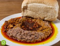 a white plate topped with meat covered in gravy and a sandwich on top of it