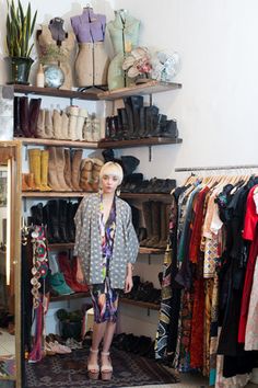 a woman standing in front of a closet full of shoes and clothing on shelves,