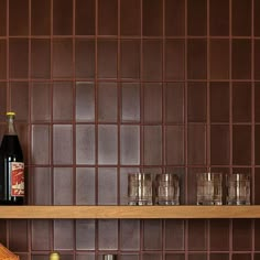 a bottle of wine sitting on top of a wooden shelf next to glasses and bottles