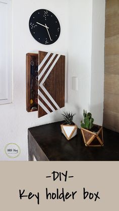 a black and white clock mounted to the side of a wall next to a plant