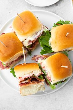 several sandwiches on a plate with toothpicks stuck in the meats and lettuce