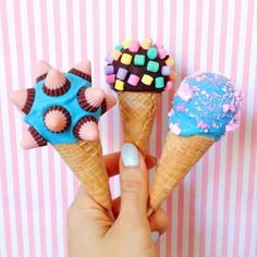 three ice cream cones with different toppings on them in front of a pink and white striped wall