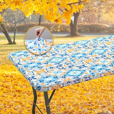 an ironing board on top of a blue and white table cloth in front of yellow leaves