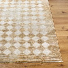 a beige and white area rug with diamond pattern on the top, sitting on a wooden floor