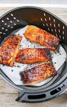 three salmon fillets in an air fryer basket