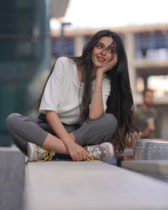 a woman is sitting on the edge of a skateboard ramp and smiling at the camera