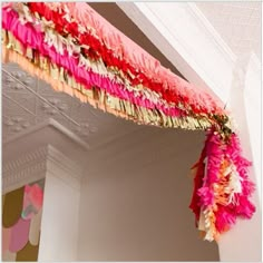 a pink and red decoration hanging from the ceiling in a room with white trimmings