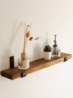 a wooden shelf with some plants and soap dispensers on it