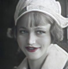 a close up of a person wearing a hat and smiling at the camera with blue eyes