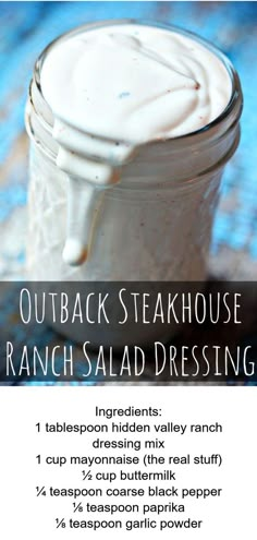 a jar filled with ranch salad dressing sitting on top of a blue tablecloth next to a