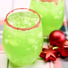 two green drinks sitting on top of a table next to christmas ornaments and decorations,