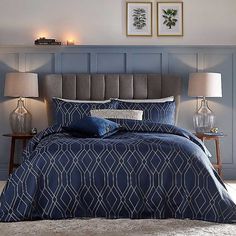 a bed with blue comforter and two lamps