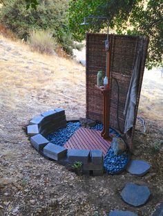 an outdoor shower in the middle of a wooded area with rocks and stones around it