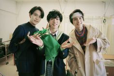 three young men standing next to each other posing for the camera with their hands in the air